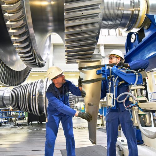workers assembling and constructing gas turbines in a modern industrial factory